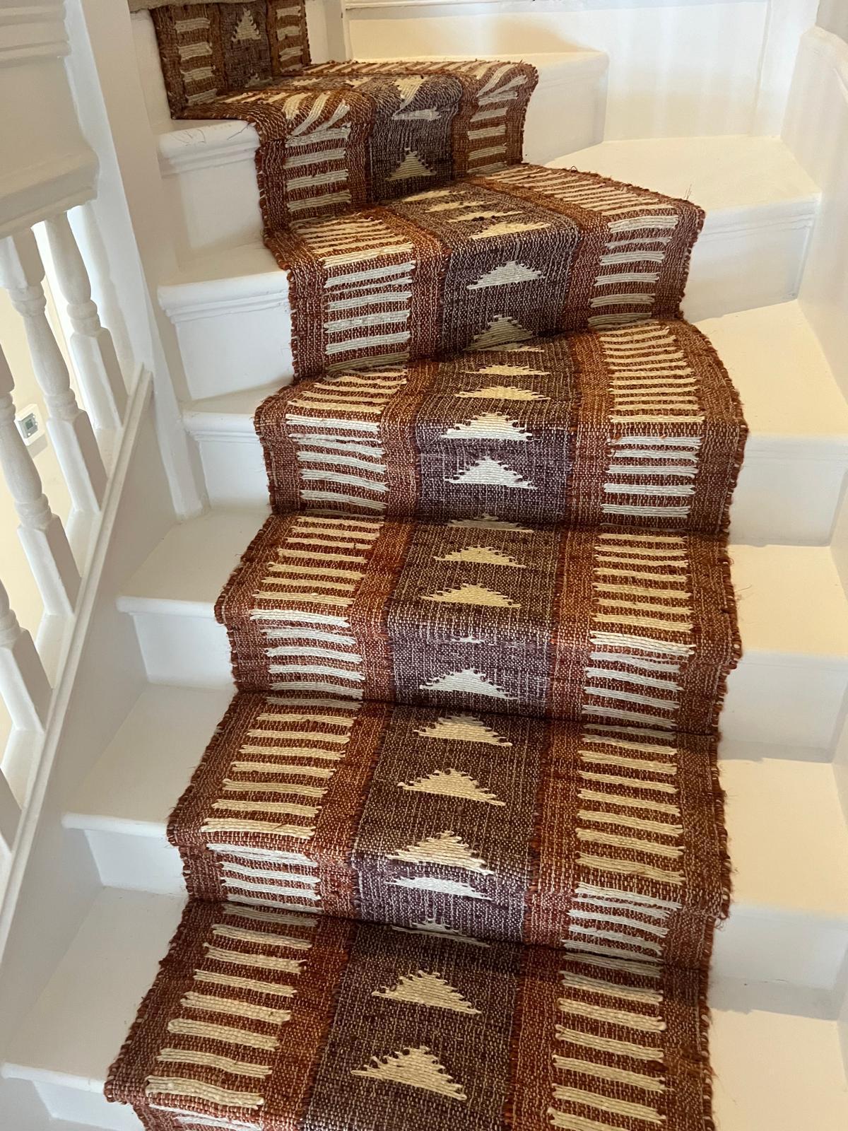 Amina Burnt Orange jute stair runner by Sophie Cooney Runner on a winding staircase, minimal white steps with designer stair runner.